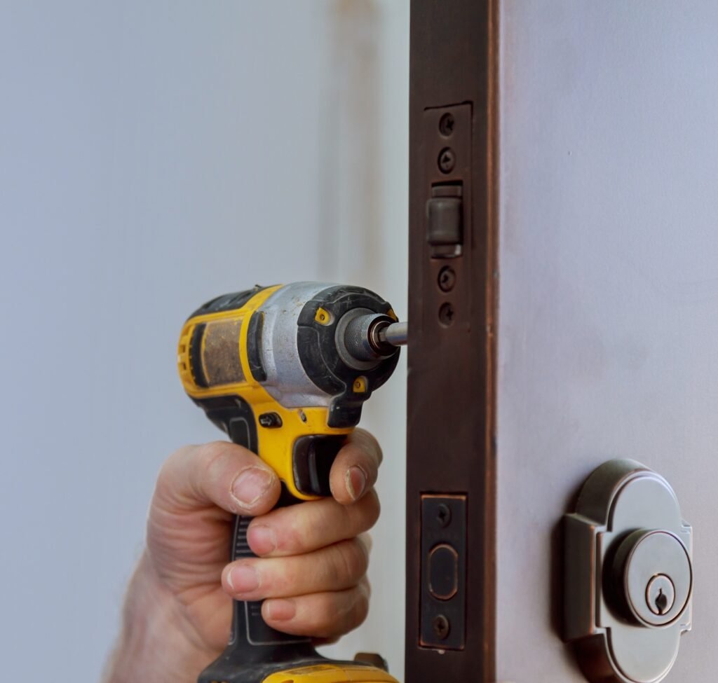 Locksmith hand holds the screwdriver in installing new house door lock
